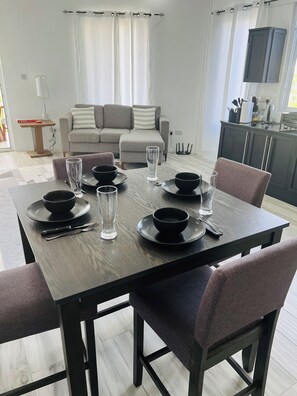 Een eetgedeelte met een tafel gedekt voor vier personen, inclusief borden, kommen, glazen en bestek.
