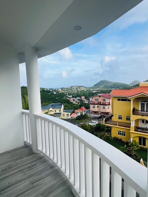 A balcony with a view of a residential area, including houses and a mountain. - Modern Diamond View Apartment 1- Close to Rodney Bay & Airport (Gros Islet)