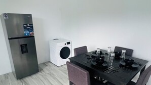 Un espace de vie compact comprenant un coin repas, un réfrigérateur intégré et un lave-linge.