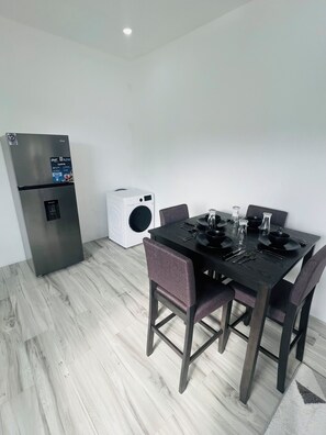 Ein kompakter Wohnraum mit Essbereich, einem Einbaukühlschrank und einer Waschmaschine.