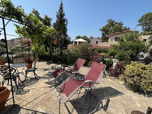 A patio area with outdoor furniture, a pergola, and a view of surrounding buildings.