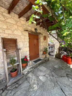 A stone building with a wooden door and a small porch area with potted plants. - Lantana Stone House.
Where the wild thyme scents the stone. (Lemona)