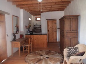 A rustic interior with a wooden dining table, chairs, a round coffee table, and a cabinet.