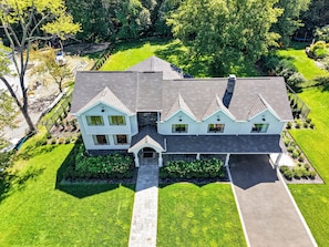 A two-story house with a central entrance, a driveway, and a well-maintained lawn.