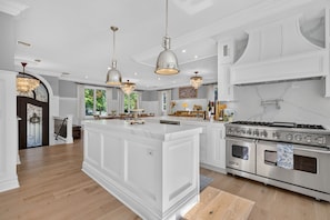 A spacious kitchen with a large island, stainless steel appliances, and pendant lighting.