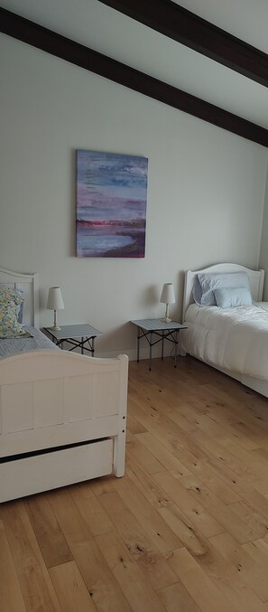 Ein Schlafzimmer mit einem Bett, Nachttischen, einem Gemälde und Holzboden.