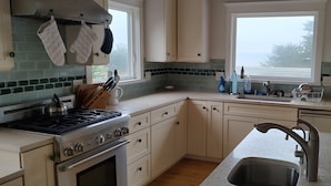 A kitchen with a stove, oven, sink, and window. - Beach house in quaint Half Moon Bay with unimpeded view and beach access (Half Moon Bay)