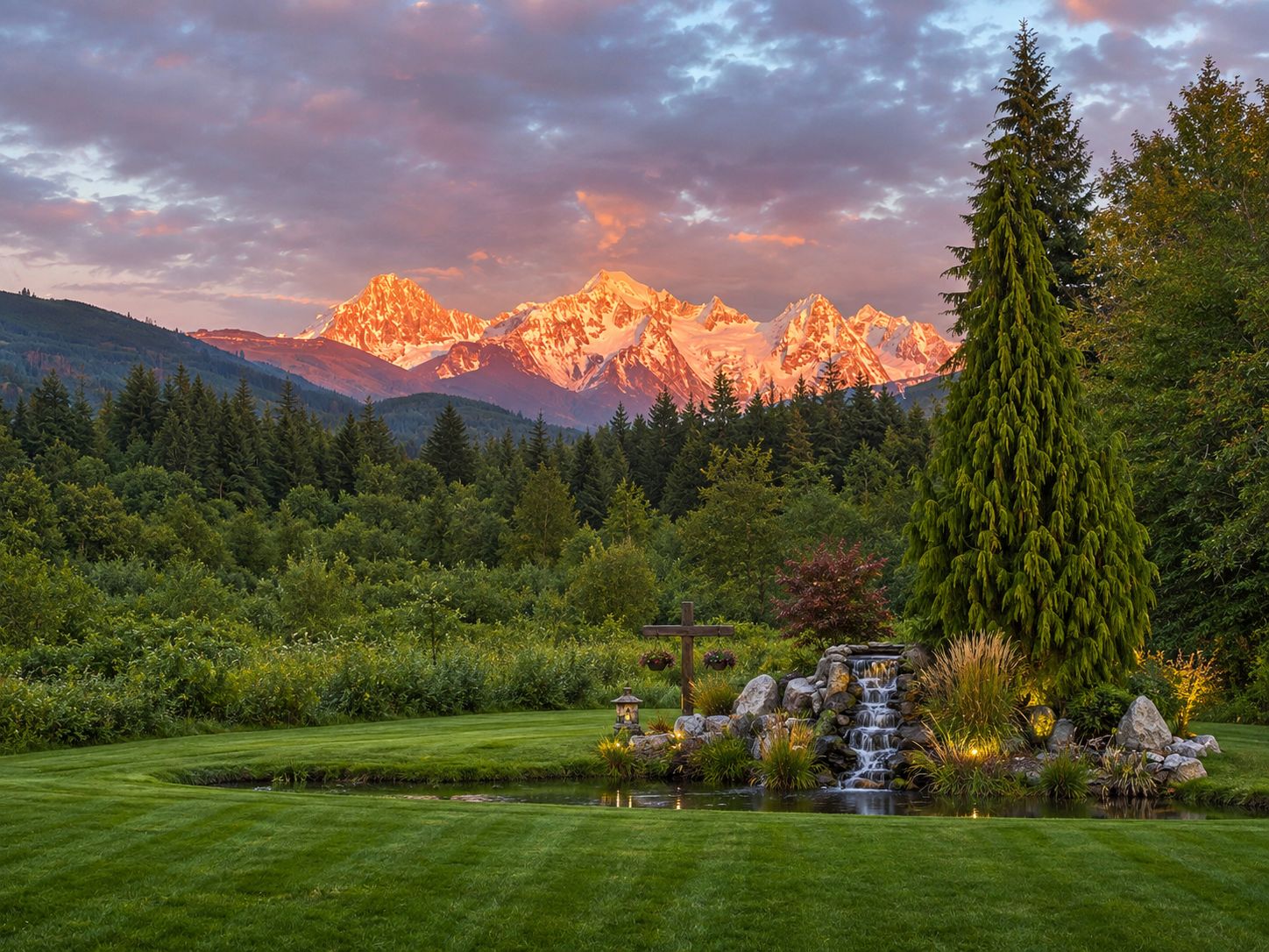 Un jardin aménagé avec un étang, un belvédère et une cascade, le tout se fondant dans un paysage de montagnes.