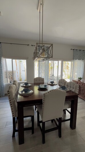 A dining area with a large table, chairs, and a hanging light fixture. - Vrbo Property (Rosarito)