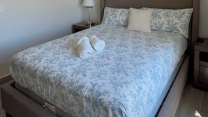 Un dormitorio con cama, mesita de noche, lámpara y ventilador de techo.