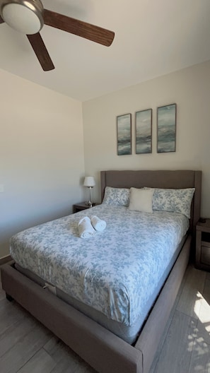 A bedroom with a bed, a nightstand, a lamp, and a ceiling fan. - Vrbo Property (Rosarito)
