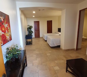 Ein Hotelzimmer mit einem Bett, einem Schreibtisch, einem Stuhl, einer Zimmerpflanze und einem Bild an der Wand.