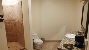 Een badkamer met een douche, toilet, wastafel en spiegel.