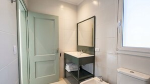 A bathroom with a green door, a white sink, a mirror, and a toilet. - Apartment for 4 with a separate bedroom (Azul)