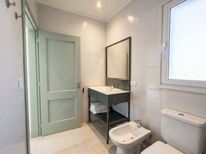 Une salle de bain avec une porte verte, un lavabo blanc, un miroir et des toilettes.