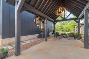 A covered patio area with a concrete floor, a wooden pergola, and a hanging light fixture.