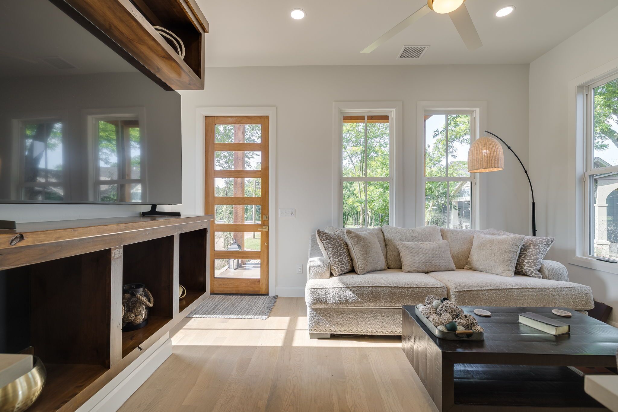 A modern living room with a sectional sofa, a flat-screen TV, and a dining area with a wooden table.