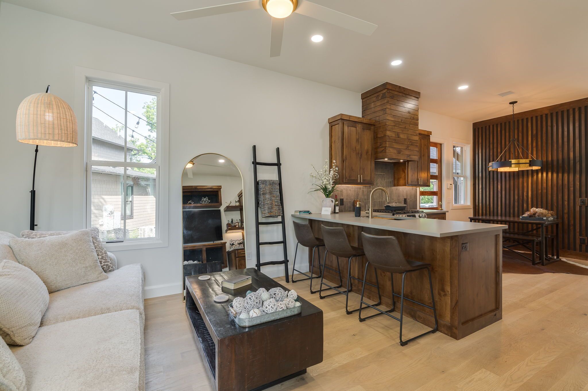 A modern kitchen with a central island, bar stools, and wooden cabinetry.