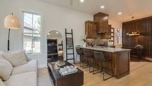 Cozinha moderna com ilha central, banquetas e armários de madeira.
