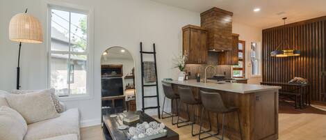 A modern kitchen with a central island, bar stools, and wooden cabinetry.
