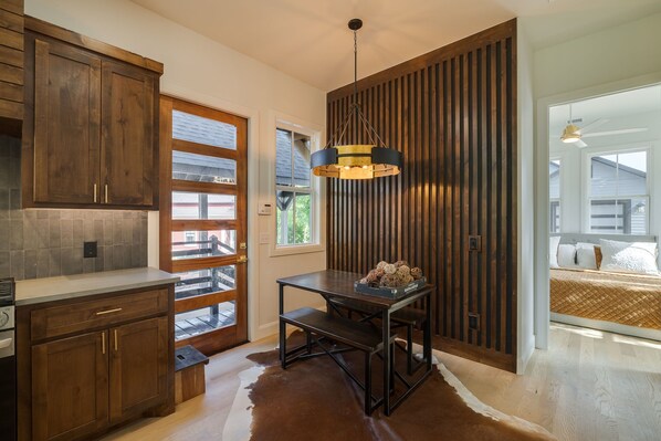A modern kitchen with wooden cabinets, a dining table, and a pendant light.