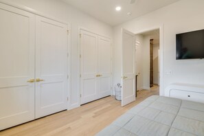Una habitación con cama, televisor en la pared y puerta que da a otra habitación.