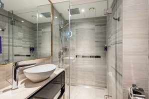 Een moderne badkamer met een douchecabine van glas, een wit wastafelbakje en een grote spiegel.