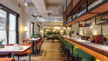 A restaurant with a long counter, multiple tables, and chairs.