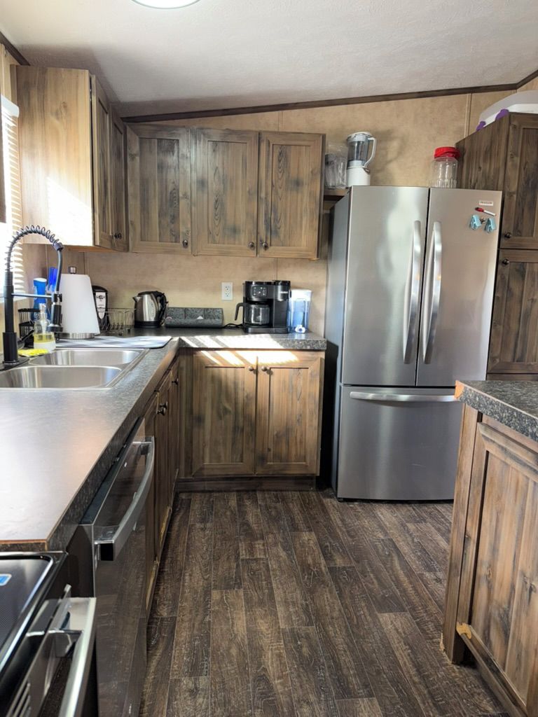 A compact kitchen with wooden cabinets, a stainless steel refrigerator, and a coffee maker.