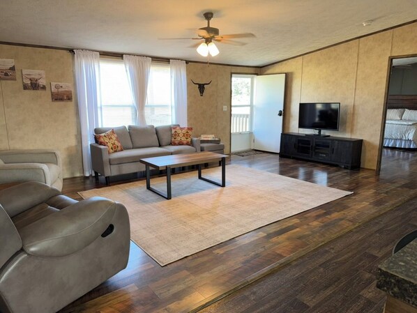 A living room with a sofa, a coffee table, a TV, and a ceiling fan.