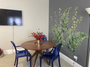 A dining area with a round table, two blue chairs, and a vase with red flowers. - Minutes to Capitol & UPMC  w/Monthly Parking (Harrisburg)