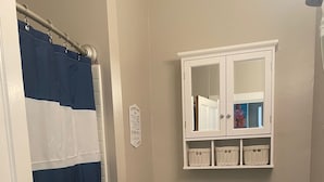 Un bagno con tenda da doccia a righe, un water, un lavandino e uno specchio con cornice decorativa.