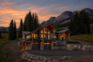 A large, multi-story log cabin with a stone foundation, multiple balconies, and a driveway leading to a garage. - Bear Scratch | Mountain Views & Modern Luxury (Crested Butte)