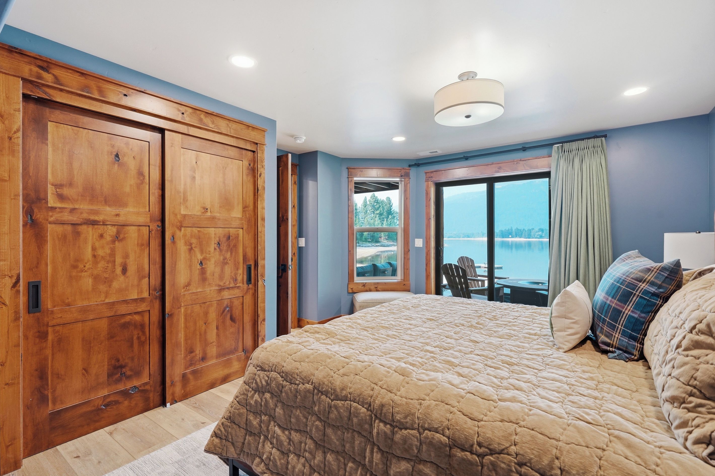 A bedroom with a large bed, wooden wardrobe, and a view of the sea.