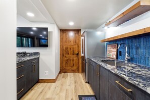Una cocina moderna con armarios oscuros, encimeras de mármol y una puerta de madera.