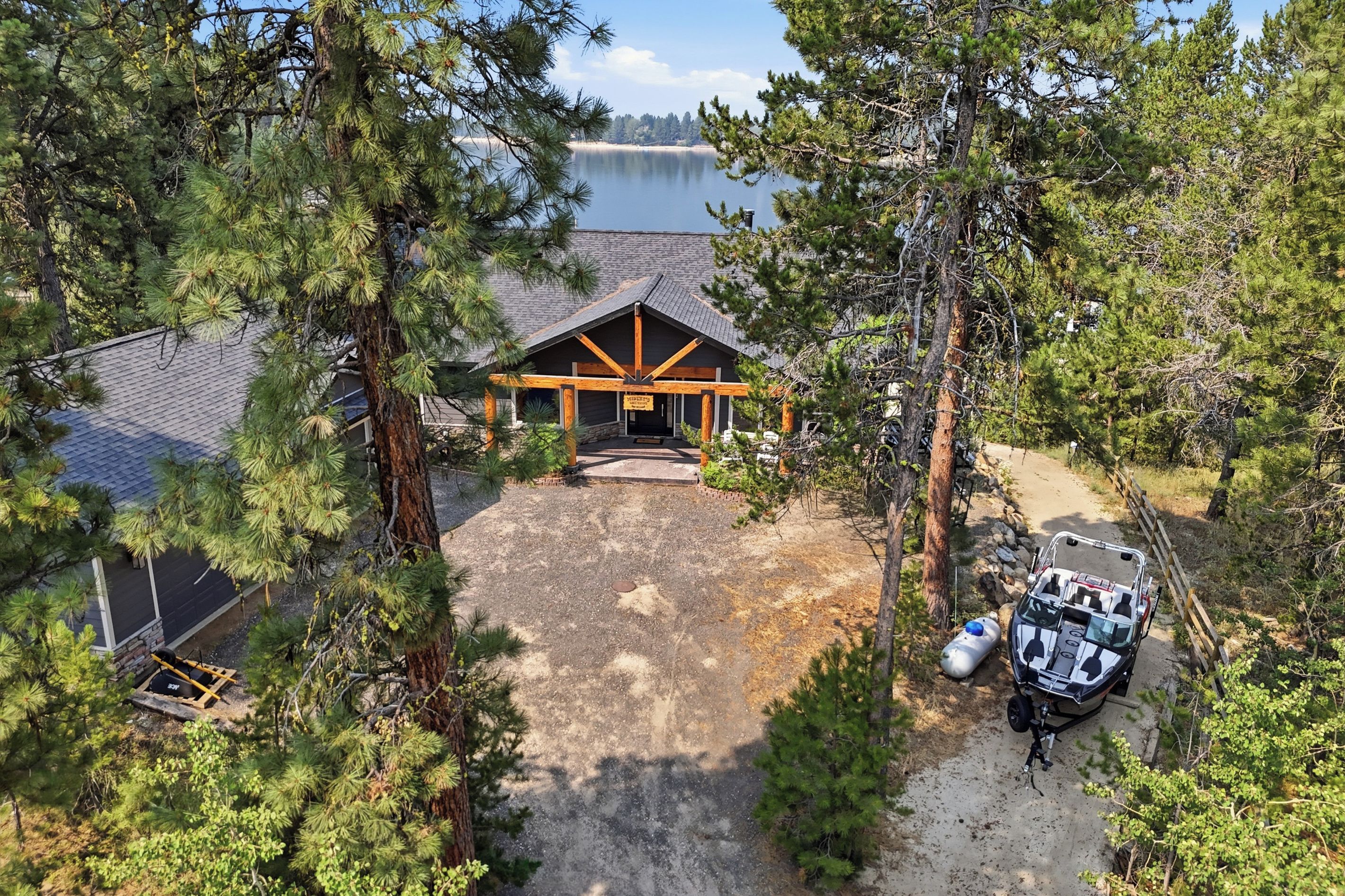 A lodge with a covered entrance, a gravel driveway, and a boat docked outside.