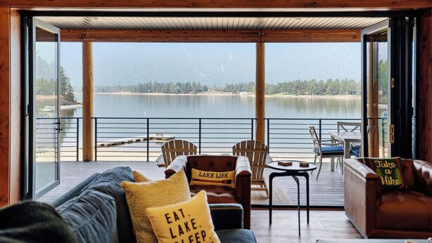 Ein Zimmer mit Seeblick, einer Holzdiele und einer Sitzecke mit Tisch und Stühlen.