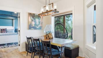 Un comedor con una mesa de madera, sillas y una lámpara colgante.