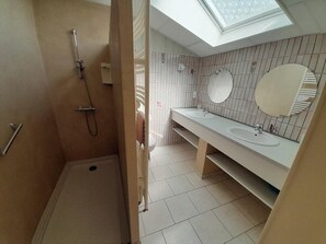 Ein Badezimmer mit Oberlicht, Dusche und zwei Waschbecken mit Spiegeln.