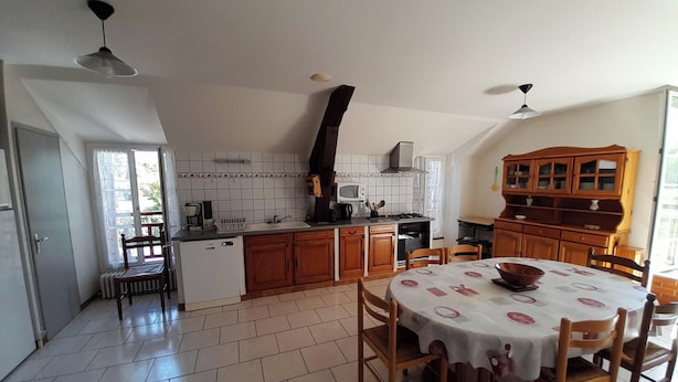 A kitchen with a dining area, a built-in oven, and a wooden cabinet.
