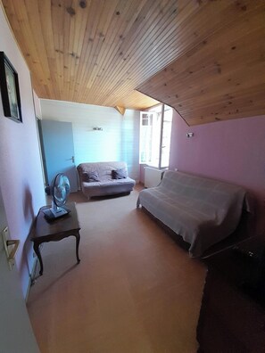 Ein Schlafzimmer mit einem Bett, einer Couch, einem kleinen Tisch und einem Ventilator.