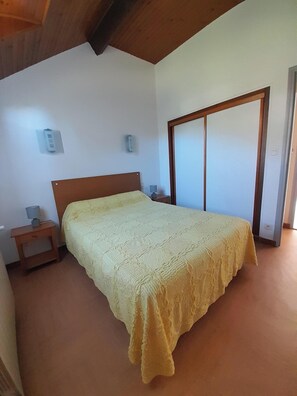 Ein Schlafzimmer mit Bett, Nachttisch, Wandlampe und einer Schiebetür.