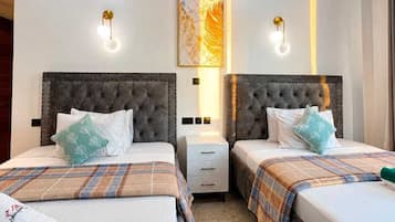 Habitación de hotel con dos camas, una mesita de noche, una obra de arte en la pared y apliques.