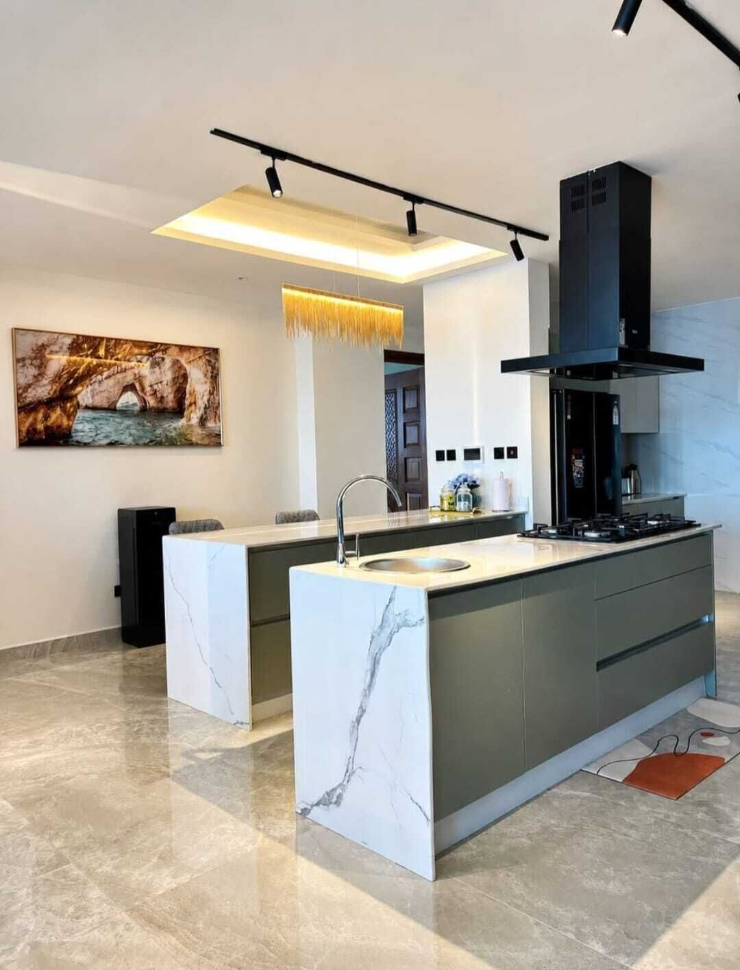 Una cocina moderna con una isla de m ármol, estufa integrada y una lámpara colgante.