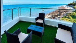 A balcony with a view of the ocean, furnished with wicker chairs and a small table. - Comforts Seaview Apartments-Nyali (Mombasa)