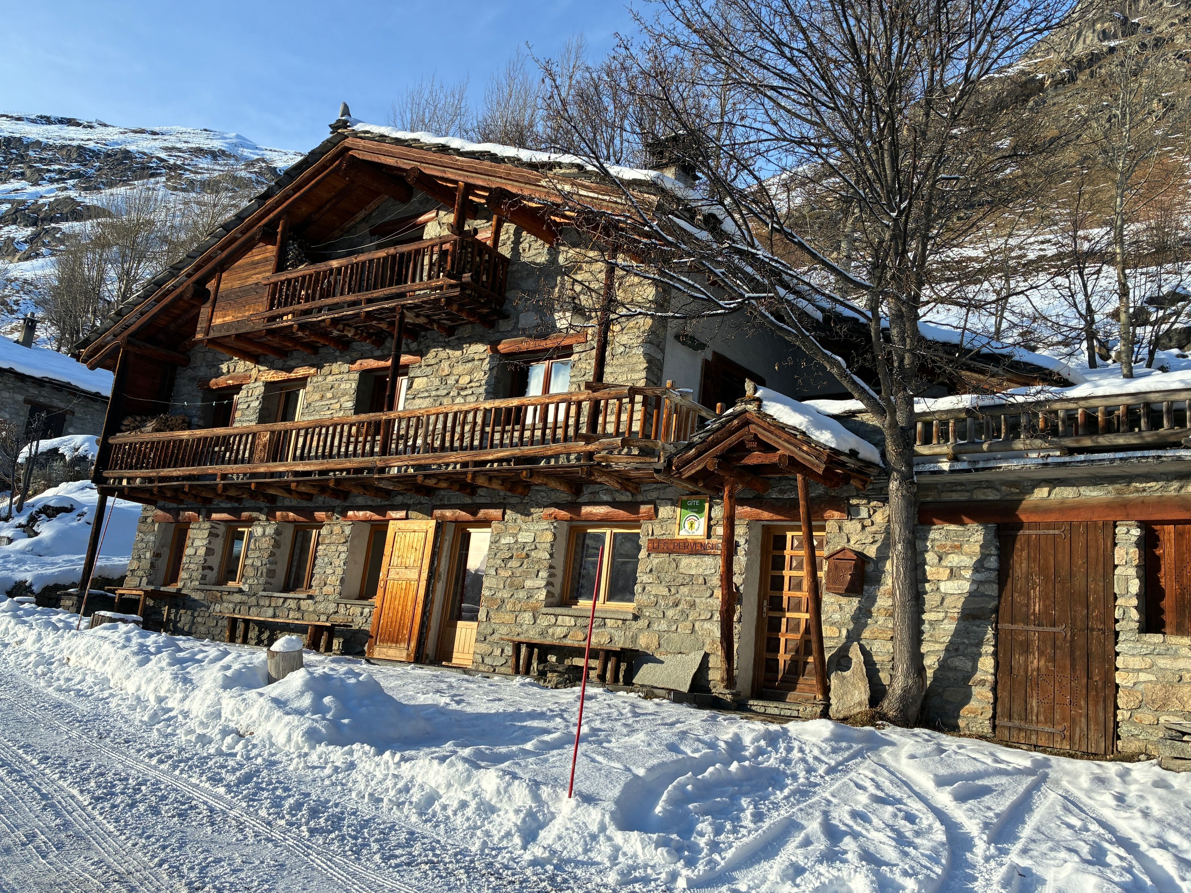 Un bâtiment en pierre doté d’un balcon en bois et d’une enseigne indiquant qu’il s’agit d’une maison d’hôtes.