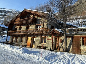 Ein Steinhaus mit einem hölzernen Balkon und einem Schild, das es als Pension kennzeichnet.