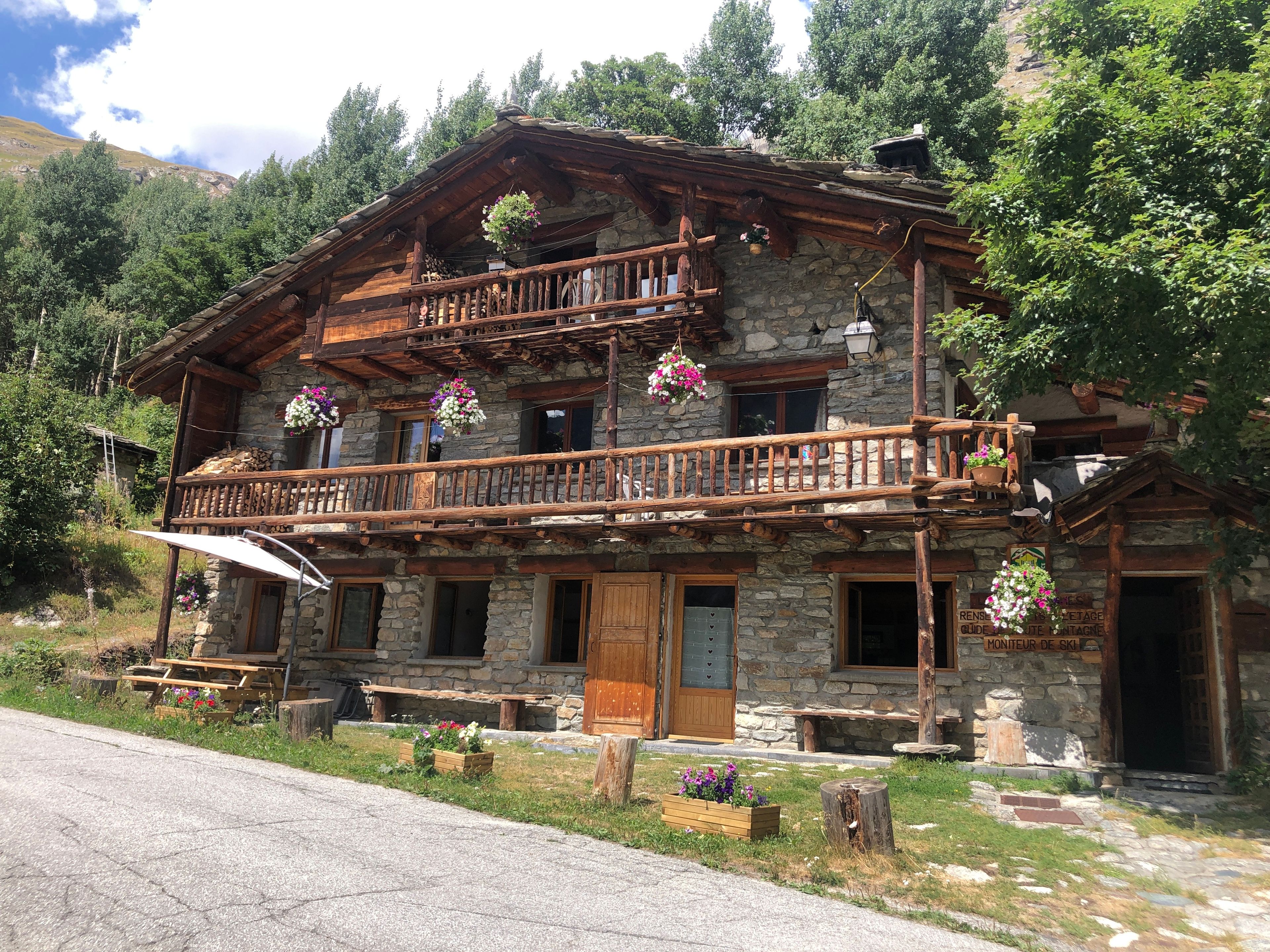 A rustic chalet with a wooden balcony, stone walls, and flower boxes.
