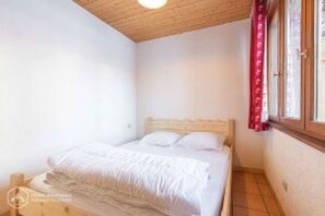 Une chambre à coucher avec un lit, un plafond en bois et une fenêtre avec des rideaux.