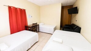 Quarto com duas camas de solteiro, uma escrivaninha com cadeira, cortina vermelha e televisão na parede.
